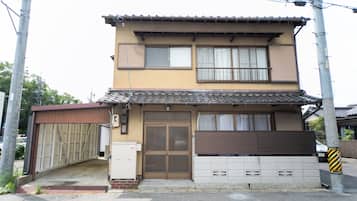 Un edificio de dos pisos con estilo arquitectónico tradicional, que presenta un tejado de baldosas y una puerta de madera.