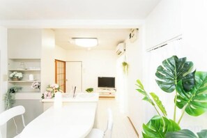 A modern interior with a dining area, a television, and a large plant. - Yokkaichi Nishishinchi Hotel (Yokkaichi)