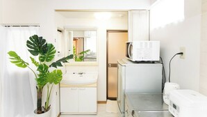 A compact hotel bathroom with a sink, mirror, and a microwave on a small table. - Yokkaichi Nishishinchi Hotel (Yokkaichi)