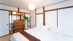A hotel room with a large bed, a wooden wardrobe, a desk with a lamp, and a potted plant. - Yokkaichi Nishishinchi Hotel (Yokkaichi)