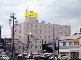 Un edificio de varios pisos con un llamativo letrero amarillo en el techo.