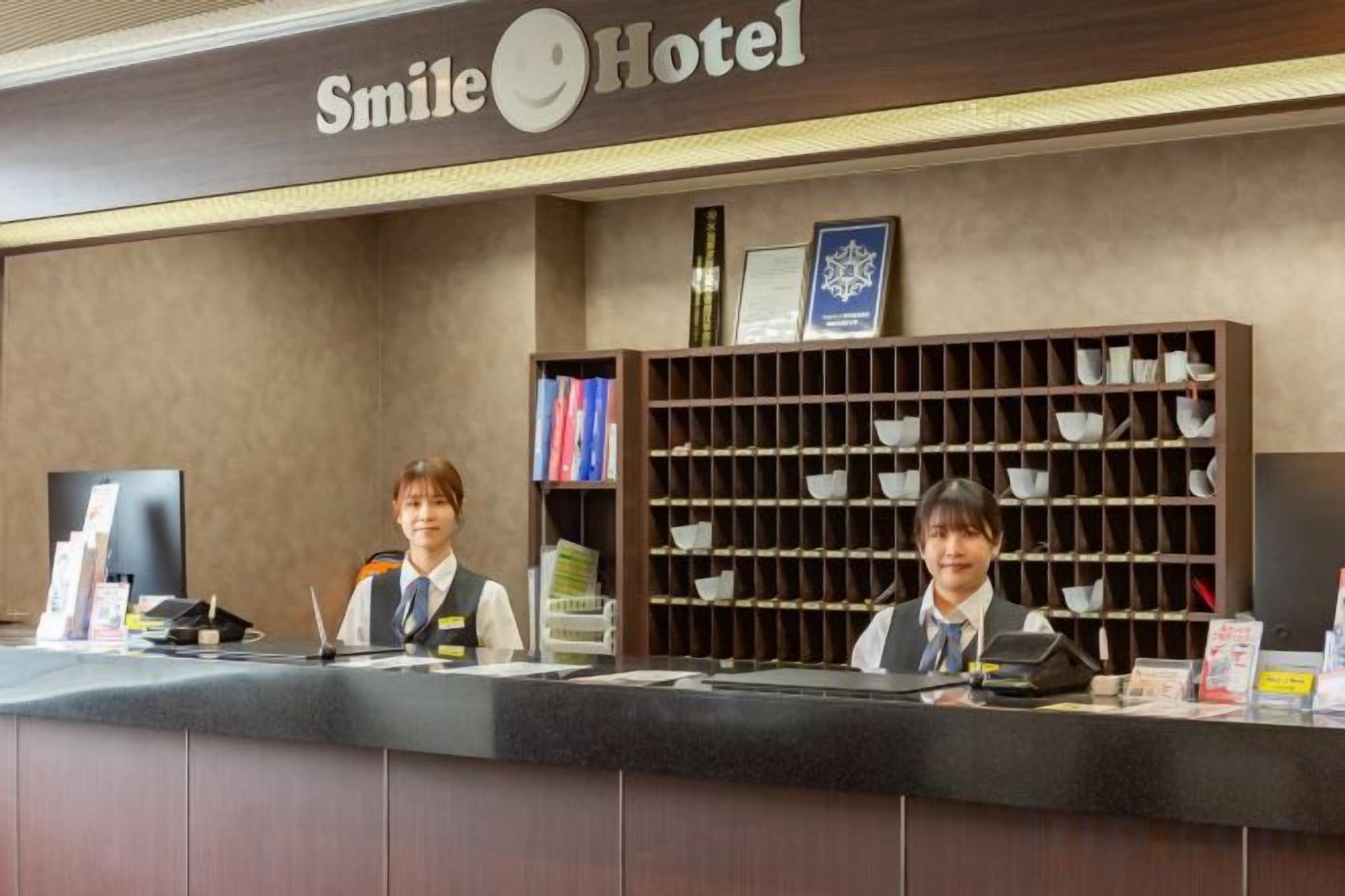 Mostrador de recepción del Hotel Smile, con una barra, una computadora y un estante con tazas.