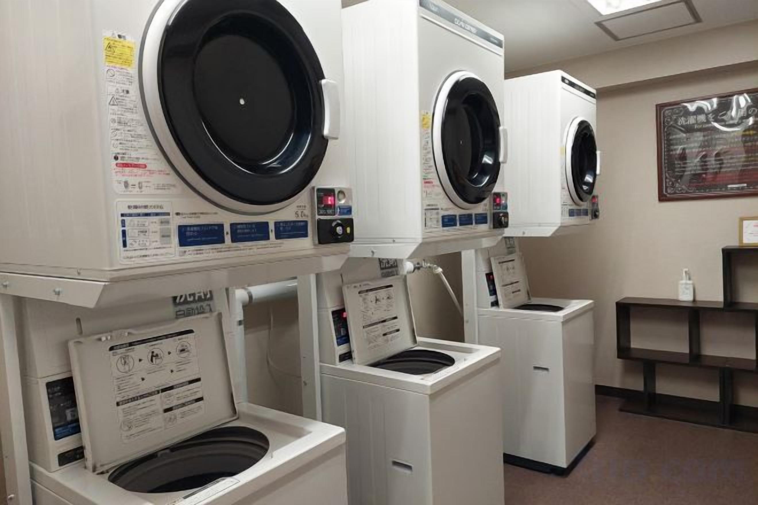 A laundry facility with multiple washing machines and dryers, arranged in a row.