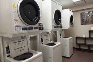 Une laverie équipée de plusieurs machines à laver et de plusieurs séchoirs, disposés en rangée.