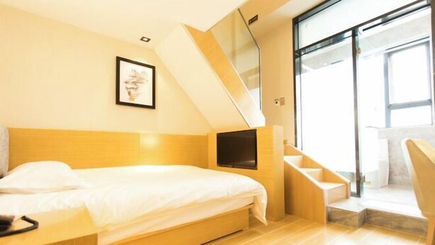 A modern bedroom with a bed, a TV, a staircase, and a large window. - Super 8 Loft(Beijing Tiananmen Qianmen Metro Station Branch) (Beijing)