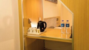 A hotel room with a wooden desk, a coffee maker, two mugs, and two water bottles. - Super 8 Loft(Beijing Tiananmen Qianmen Metro Station Branch) (Beijing)