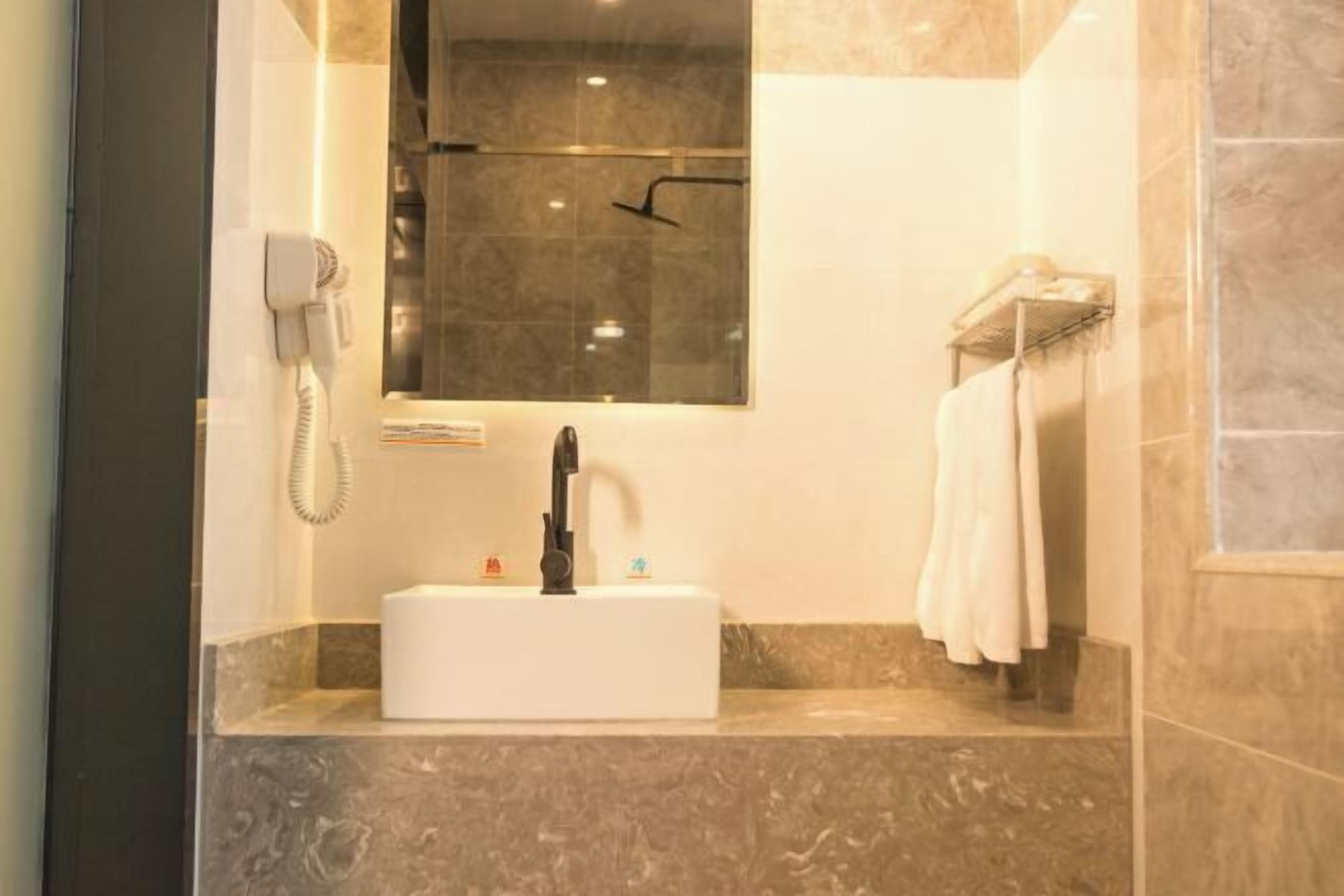 Ein modernes Badezimmer mit einer Duschkabine aus Glas, einem weißen Waschbecken und einem an der Wand montierten Föhn.