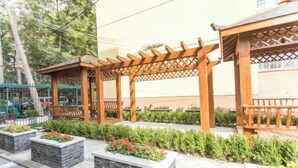 A wooden pergola structure with benches, surrounded by landscaped planters with various plants. - Super 8 Loft(Beijing Tiananmen Qianmen Metro Station Branch) (Beijing)