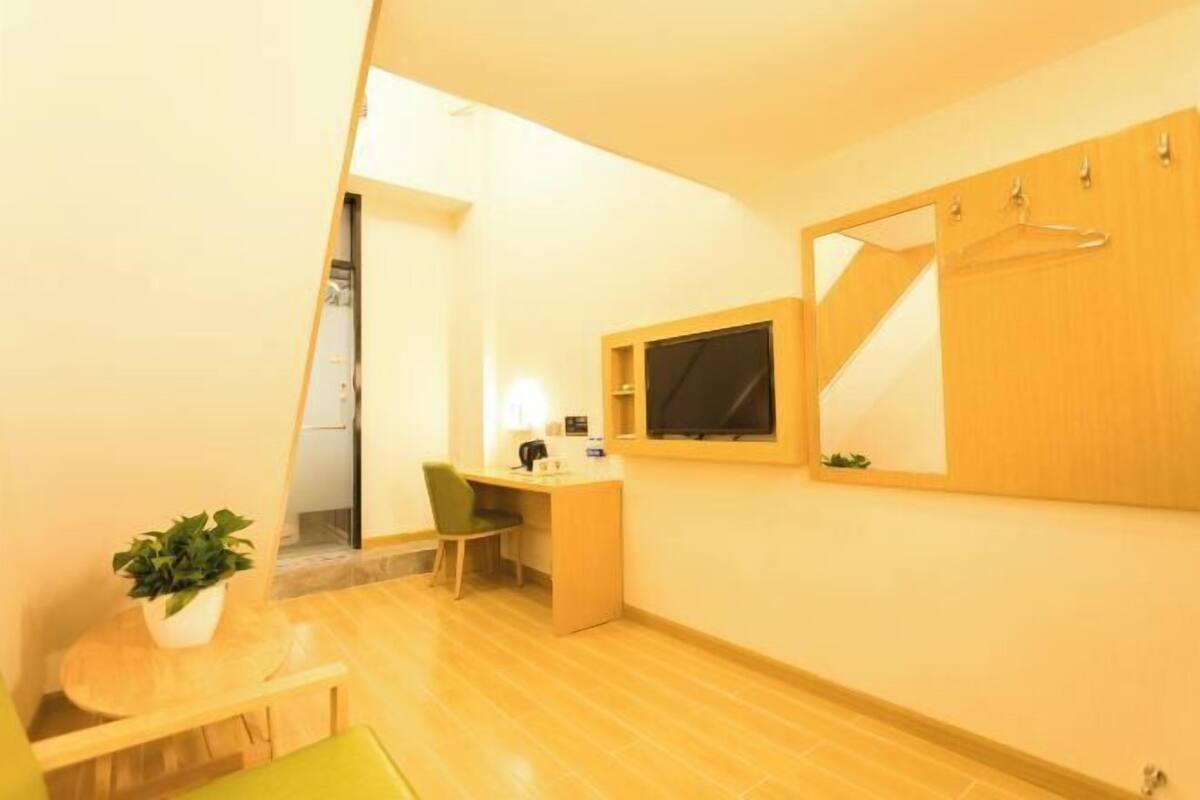 A compact room with a desk, chair, and a mirror on the wall.