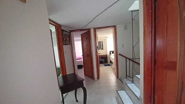 A hallway with a staircase leading to a bedroom.