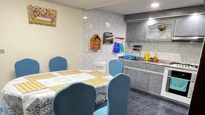 A modern kitchen with grey tiles, a stove, oven, and a dining area with a table and chairs.