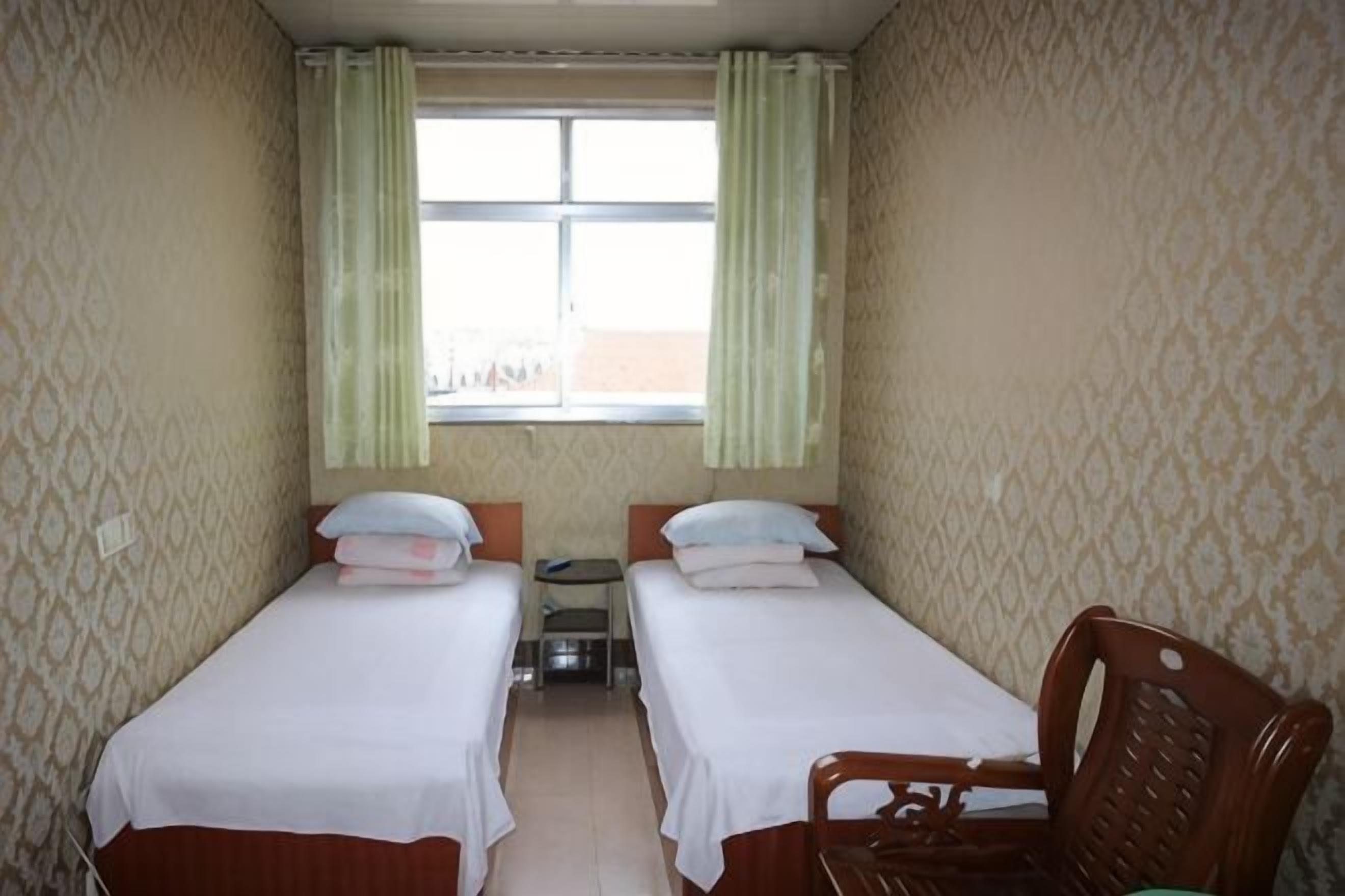 A room with two beds, a small table, and a chair.