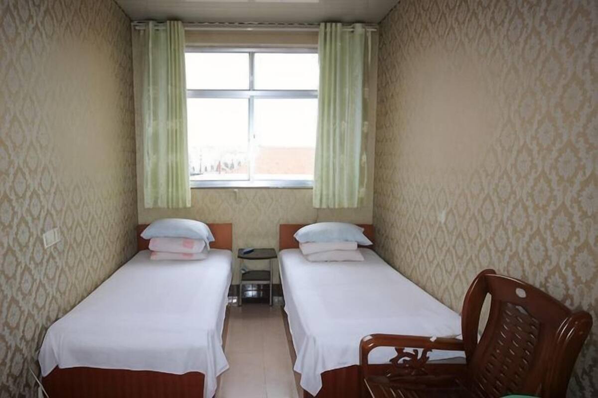 Quarto com duas camas, uma mesinha e uma cadeira.