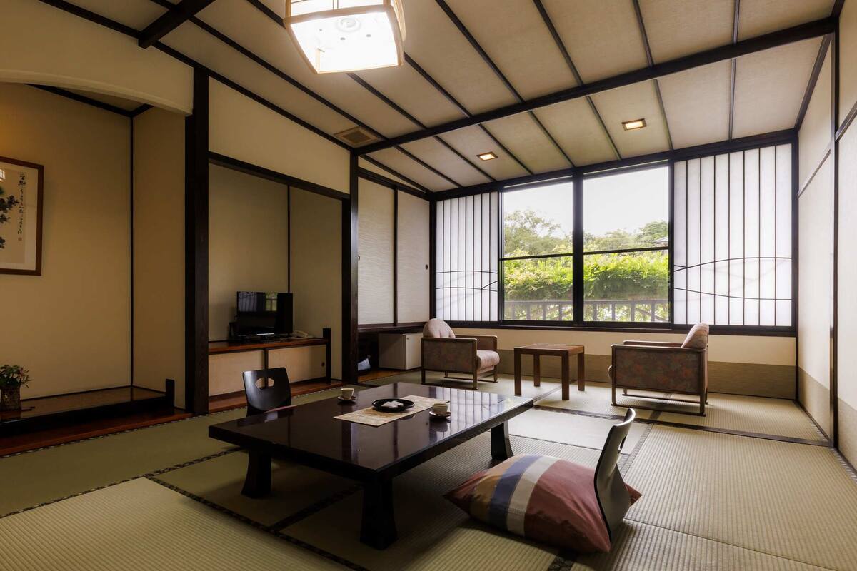 Une pièce de style japonais traditionnel, avec un sol recouvert de tatamis, une table basse et des portes coulissantes.