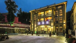 Un hotel de estilo arquitectónico clásico, con una entrada destacada que incluye un balcón y señalización iluminada.
