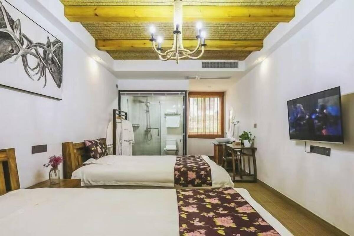 Une chambre d’hôtel avec deux lits, un téléviseur, un lustre et un espace douche.