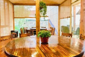 Un intérieur en bois avec une table ronde, des chaises et une plante suspendue.