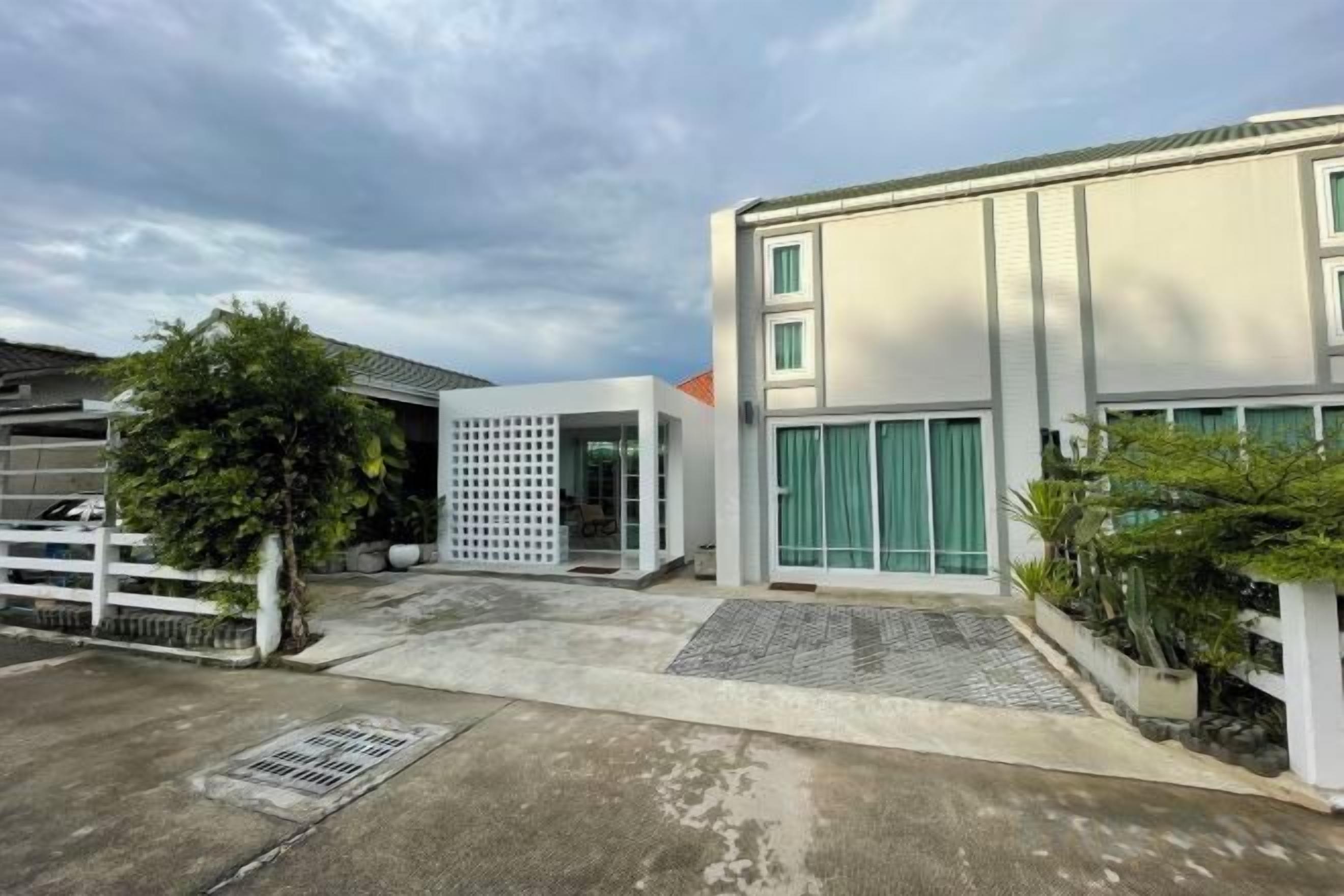 Un bâtiment moderne doté d’un garage, d’une entrée abritée et d’un petit jardin.