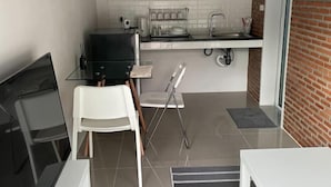A compact kitchen with a black grill, white chairs, and a small dining table. - Sealoft,Pattaya (Pattaya)