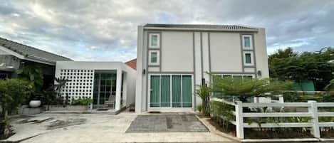 A modern two-story building with a flat roof, a gated entrance, and a paved driveway.