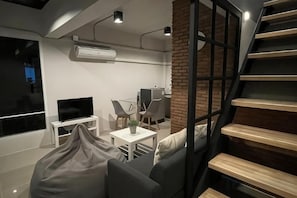 A modern living space with a staircase, a flat-screen TV, a dining area, and a brick wall. - Sealoft,Pattaya (Pattaya)