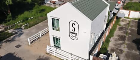 A white building with a green roof, a white fence, and a logo on the side.