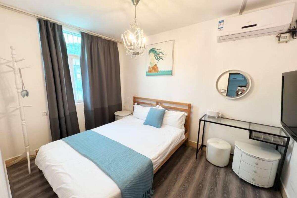 A hotel room with a bed, bedside table, lamp, and a TV.