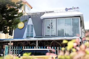 A building with a balcony, a sign that reads 'Bonjour,' and a fence in front.