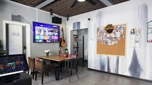 A modern office space with a large flat-screen TV, a guitar, a bulletin board with photos, and a dining area with a table and chairs. - Favorite Bonjour Shenzhen Seaview Meisu (Shenzhen)