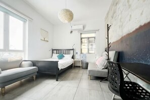 Ein modernes Schlafzimmer mit einem Bett, einer Couch, einem Schreibtisch und einem großen Gemälde.