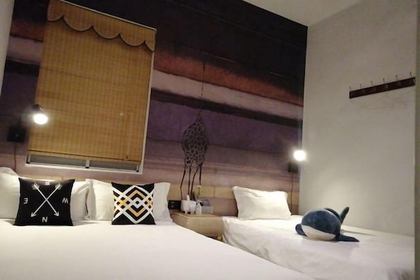 Une chambre d’hôtel avec deux lits, une grande fresque murale, une fenêtre avec un rideau et une table de chevet avec une lampe.