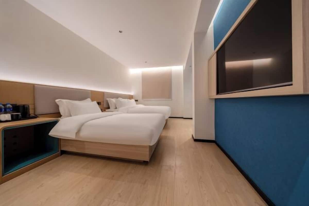 A modern hotel room with a bed, bedside table, and a large window.