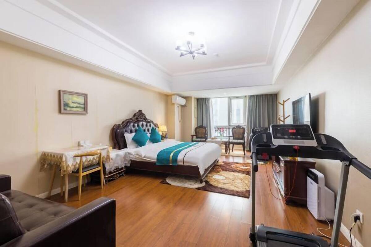 Une chambre d’hôtel équipée d’un lit, d’un bureau, d’un tapis de course et offrant une vue sur l’extérieur.