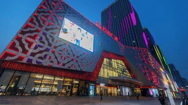 Ein modernes Gebäude mit einer großen digitalen Werbetafel und einer Fassade mit geometrischen Mustern.