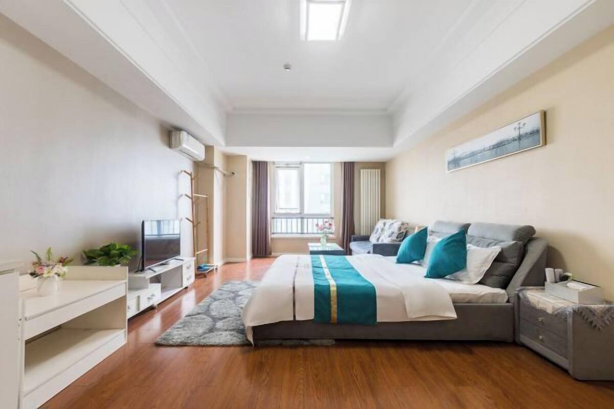 Une chambre d’hôtel moderne équipée d’un grand lit, d’une télévision, d’un bureau et d’une fenêtre avec des rideaux.