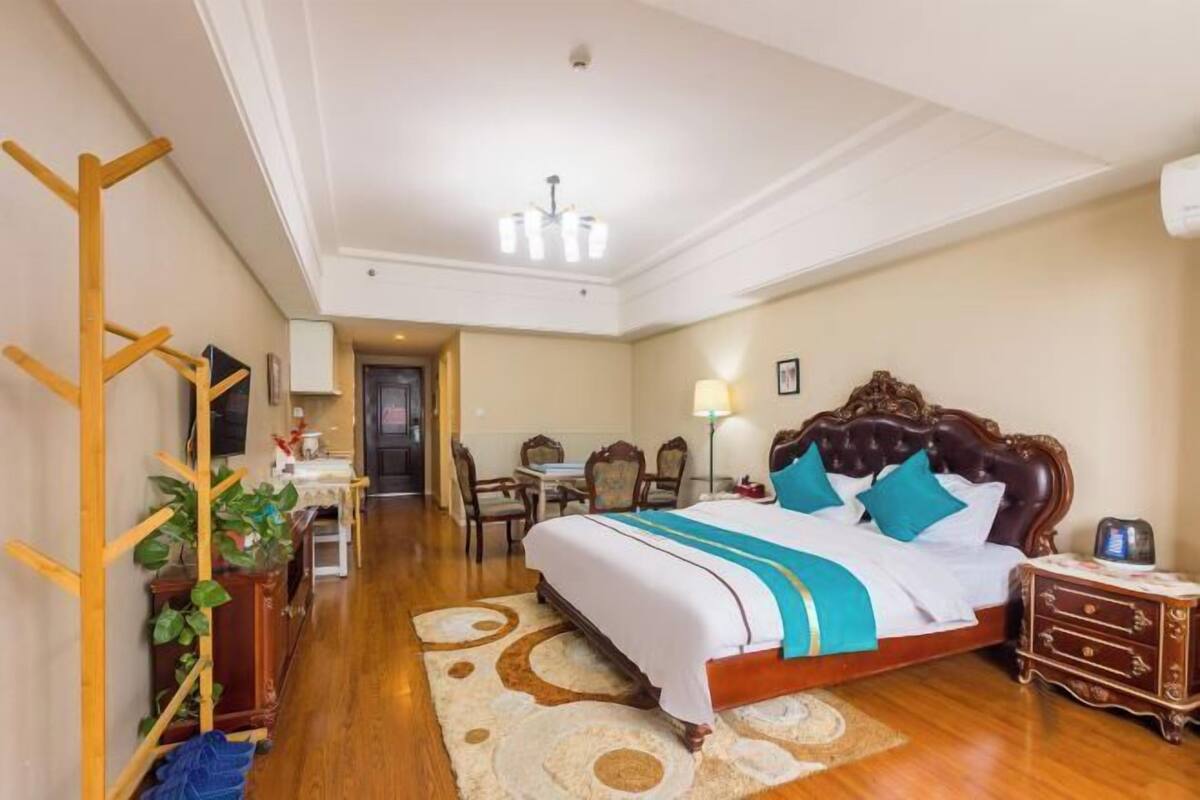 Une chambre d’hôtel avec un grand lit, un plancher en bois, un bureau avec une chaise, une lampe et une armoire.