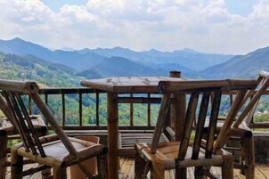 Una terraza de madera con mesa y sillas que da a un paisaje montañoso.