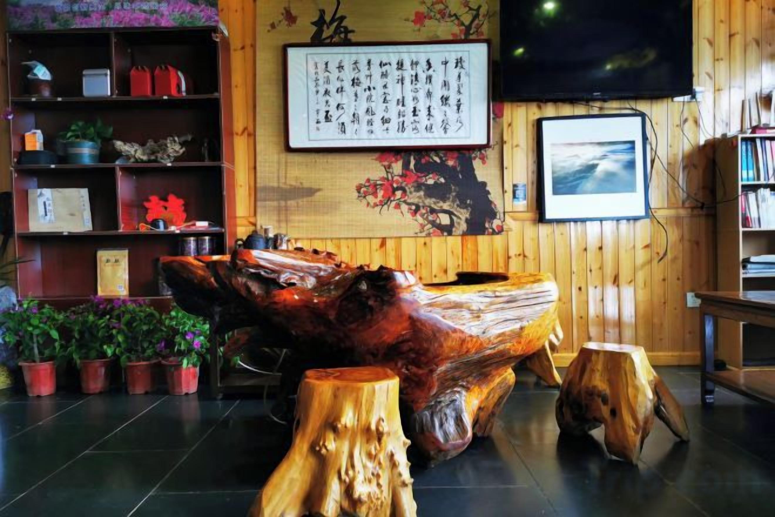 Una habitación con una gran escultura de madera, una estantería con diversos objetos y una pared decorada con obras enmarcadas.