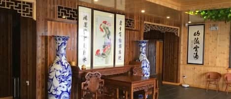 A traditional room with wooden paneling, a dining table with chairs, and two large vases with blue patterns.