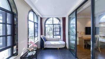 A modern room with a curved sofa, large windows, a desk, and a glass partition.