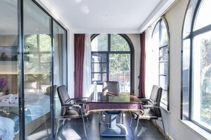 Una habitación con separador de vidrio, una mesa de comedor con sillas y ventanas amplias.