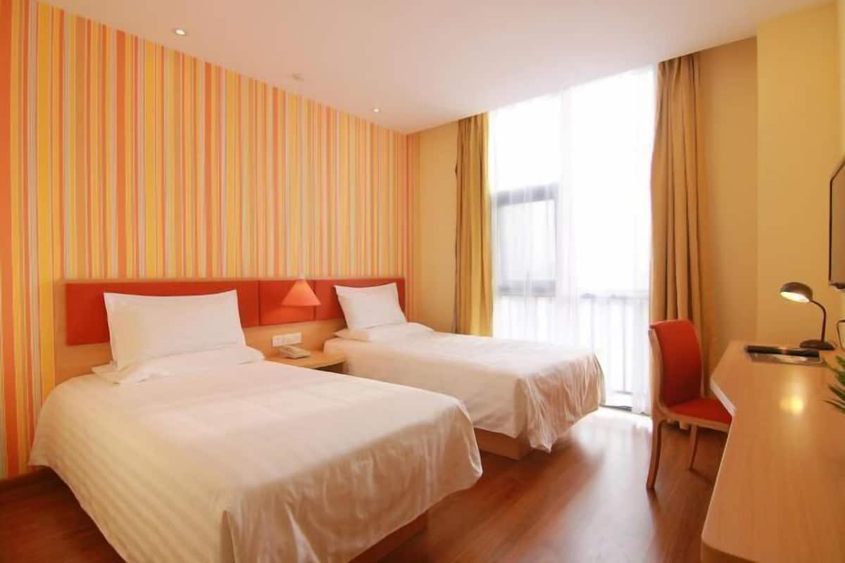 A hotel room with two beds, a desk, and a chair.
