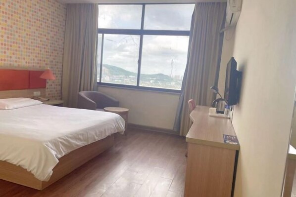 A hotel room with a bed, a desk, a chair, and a large window with a view of the city. - Homeinn Hotel (Jiangyin New World Commercial Plaza) (Jiangyin)