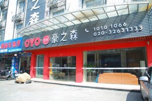 Een winkel met een rood luifel en glazen ramen, waarop een bord met contactgegevens staat.