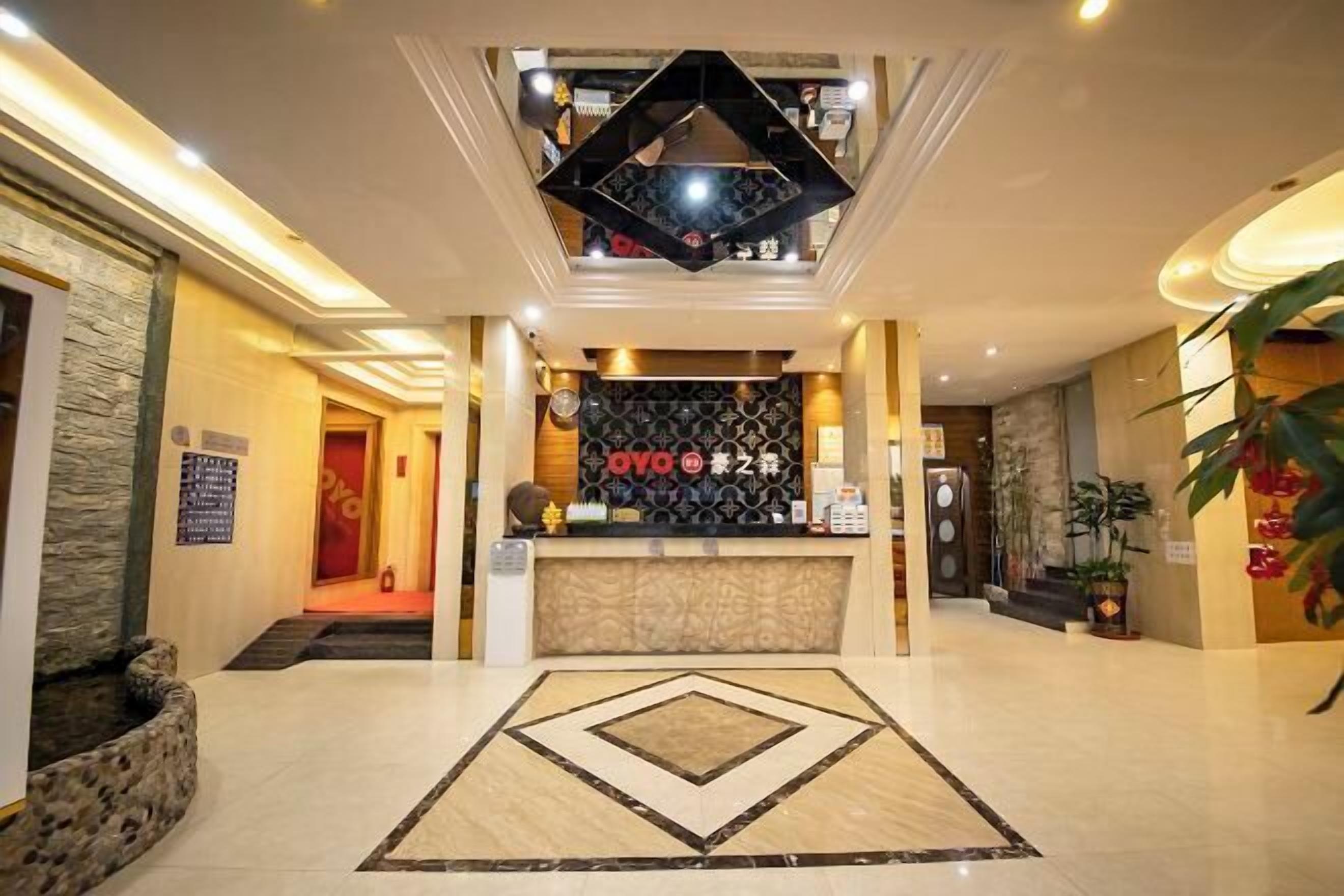 A hotel lobby with a reception desk, a geometric patterned floor, and a stone accent wall. - Haozhisen Apartment (Guangzhou)