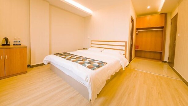 A hotel room with a bed, a wardrobe, and a bedside table. - Haozhisen Apartment (Guangzhou)