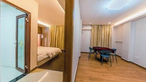 A hotel room with a bed, a table with chairs, a glass door, and a curtain. - Haozhisen Apartment (Guangzhou)