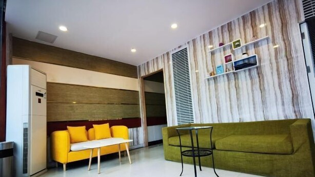 Un salon moderne avec un canapé jaune, un canapé vert et une petite table.