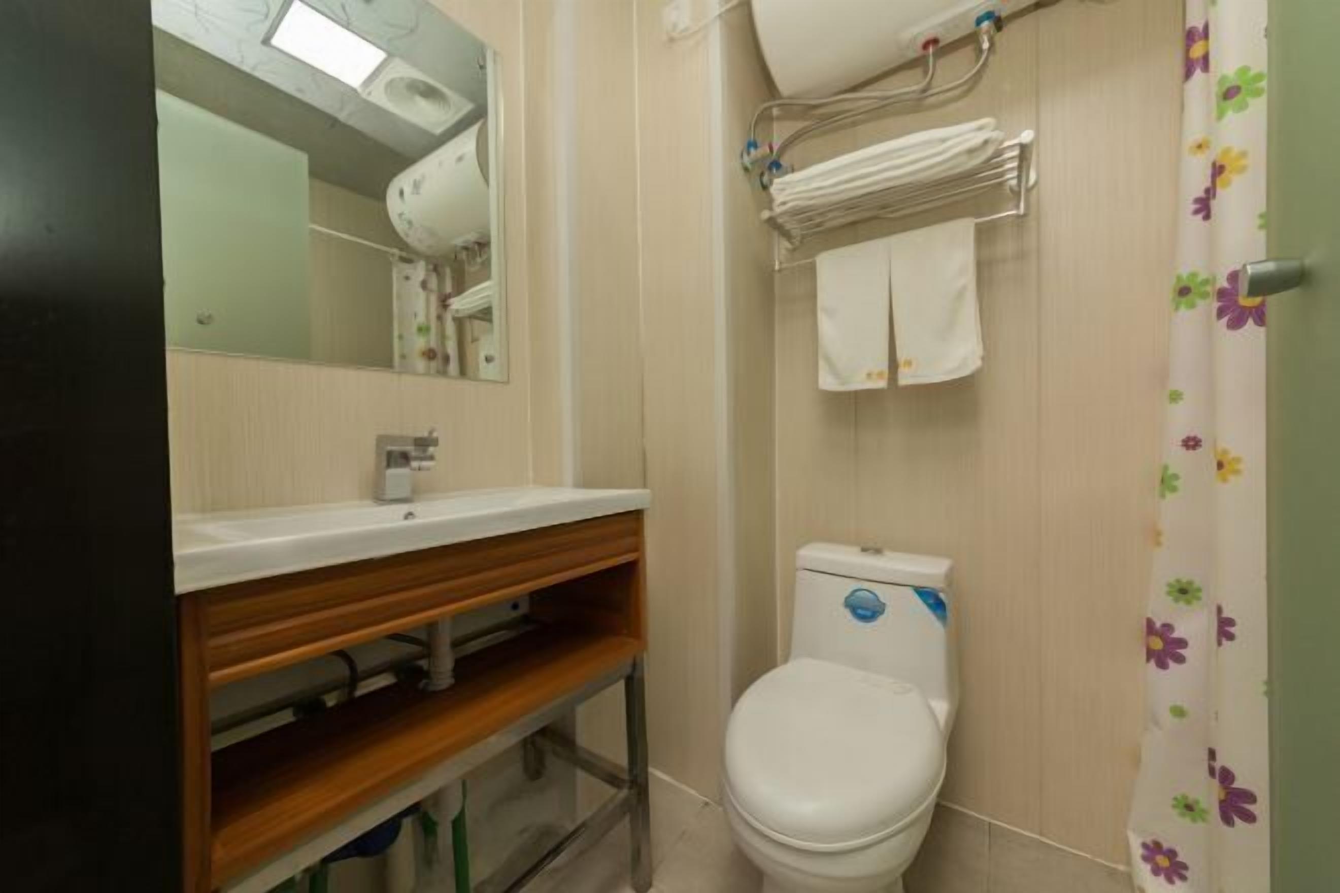 A bathroom with a toilet, a sink, a mirror, and a shower curtain.