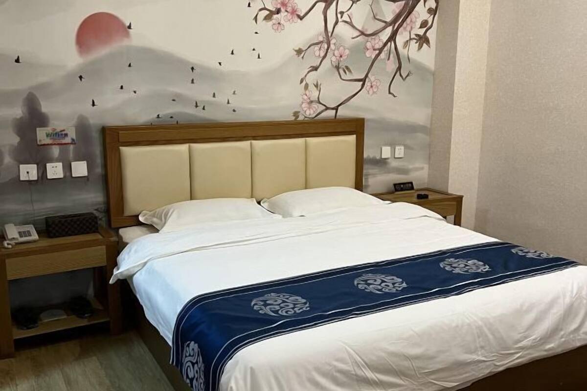 Ein Hotelzimmer mit einem Bett, Nachttischen, einem Telefon und einem Wandbild.